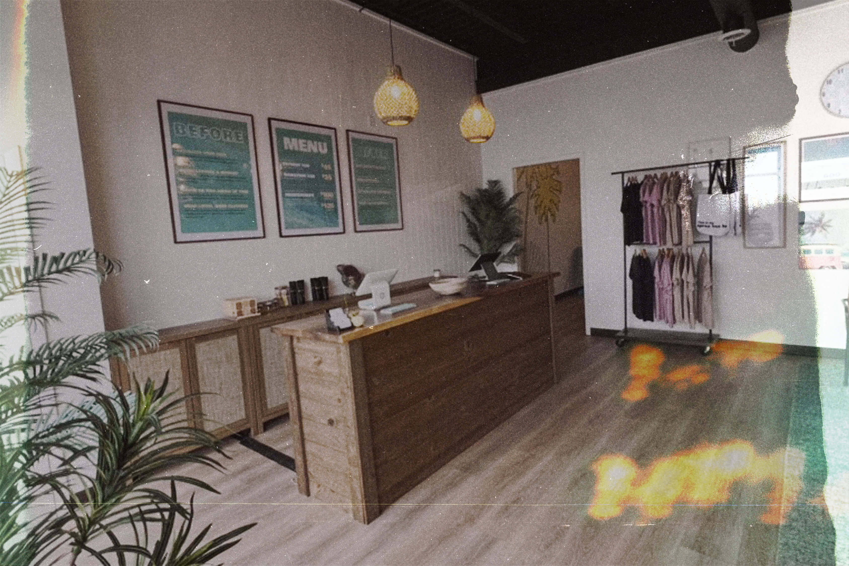 Inside Everglow Spray Tan studio — warm wood counter, teal accents, boho decor