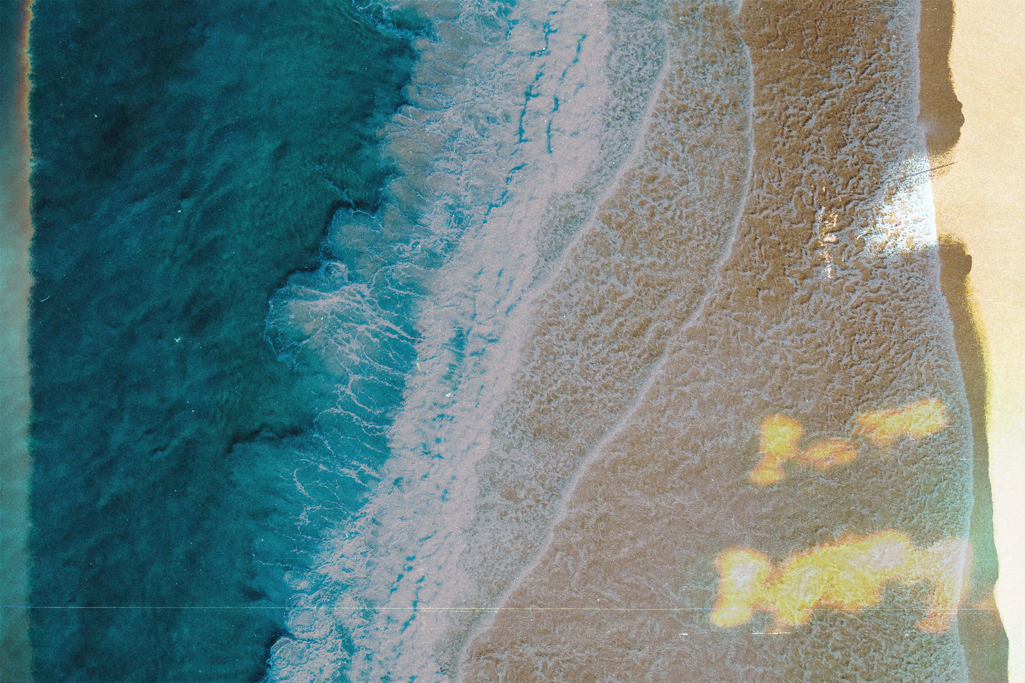 Beach aerial with golden sand and teal ocean
